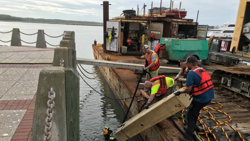 Fiberglass jacket to encase piling handed to diver.